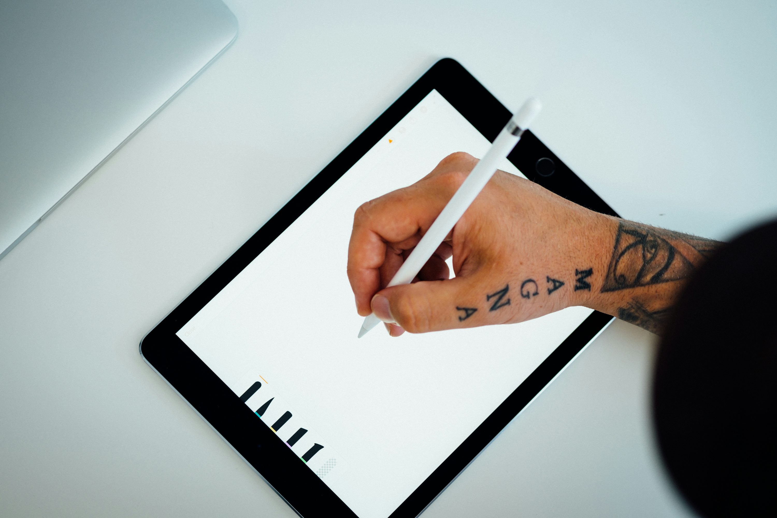 Close-up of a hand using an Apple Pencil to write digital notes on an iPad Pro screen in a modern home office setting