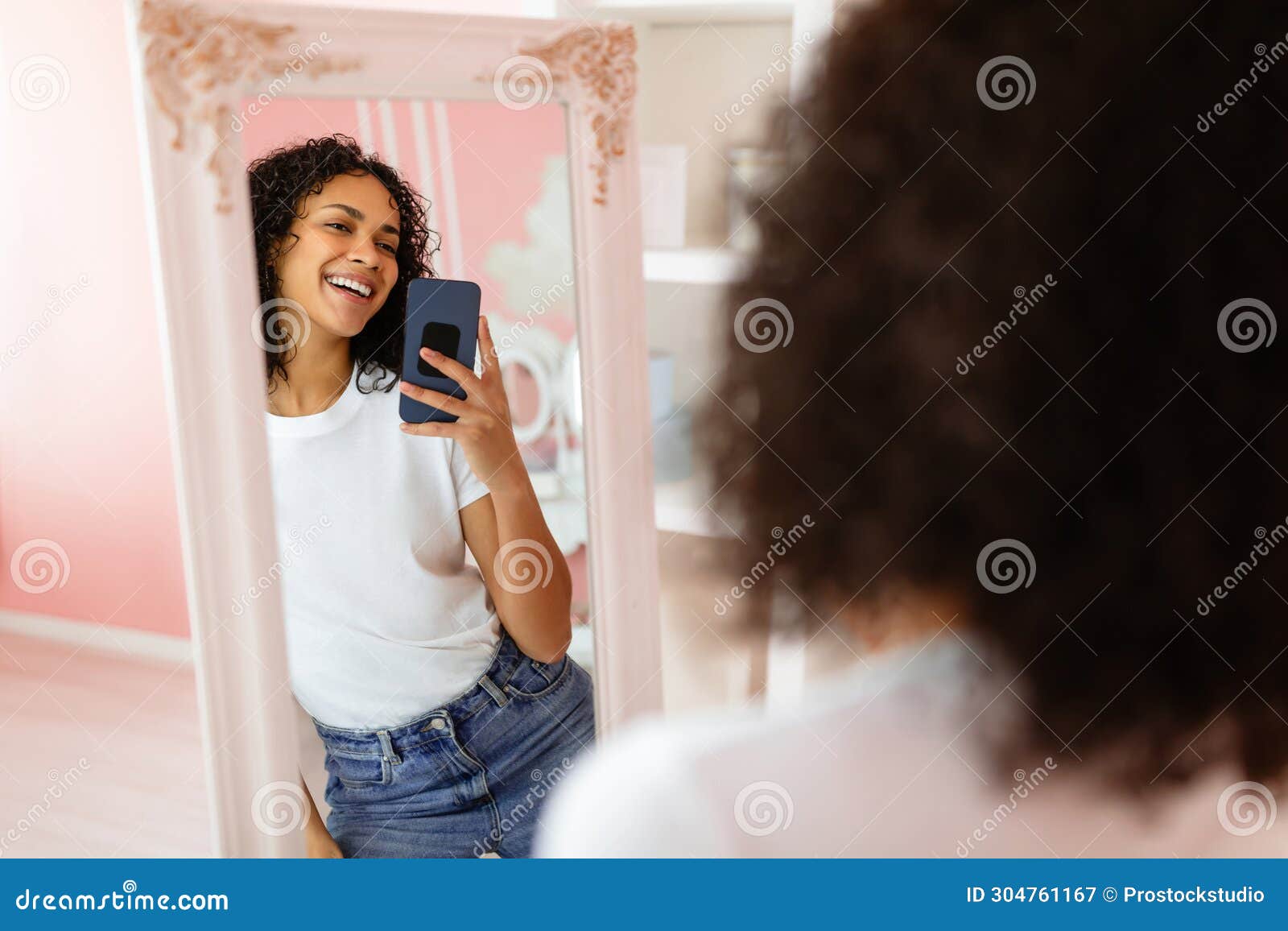 Young Canadian woman taking a mirror selfie with a smartphone, showcasing casual lifestyle fashion