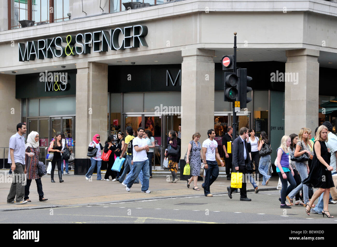 Une foule animée de personnes diverses marchant sur une rue commerçante londonienne bondée, tenant des sacs de courses sous un ciel couvert