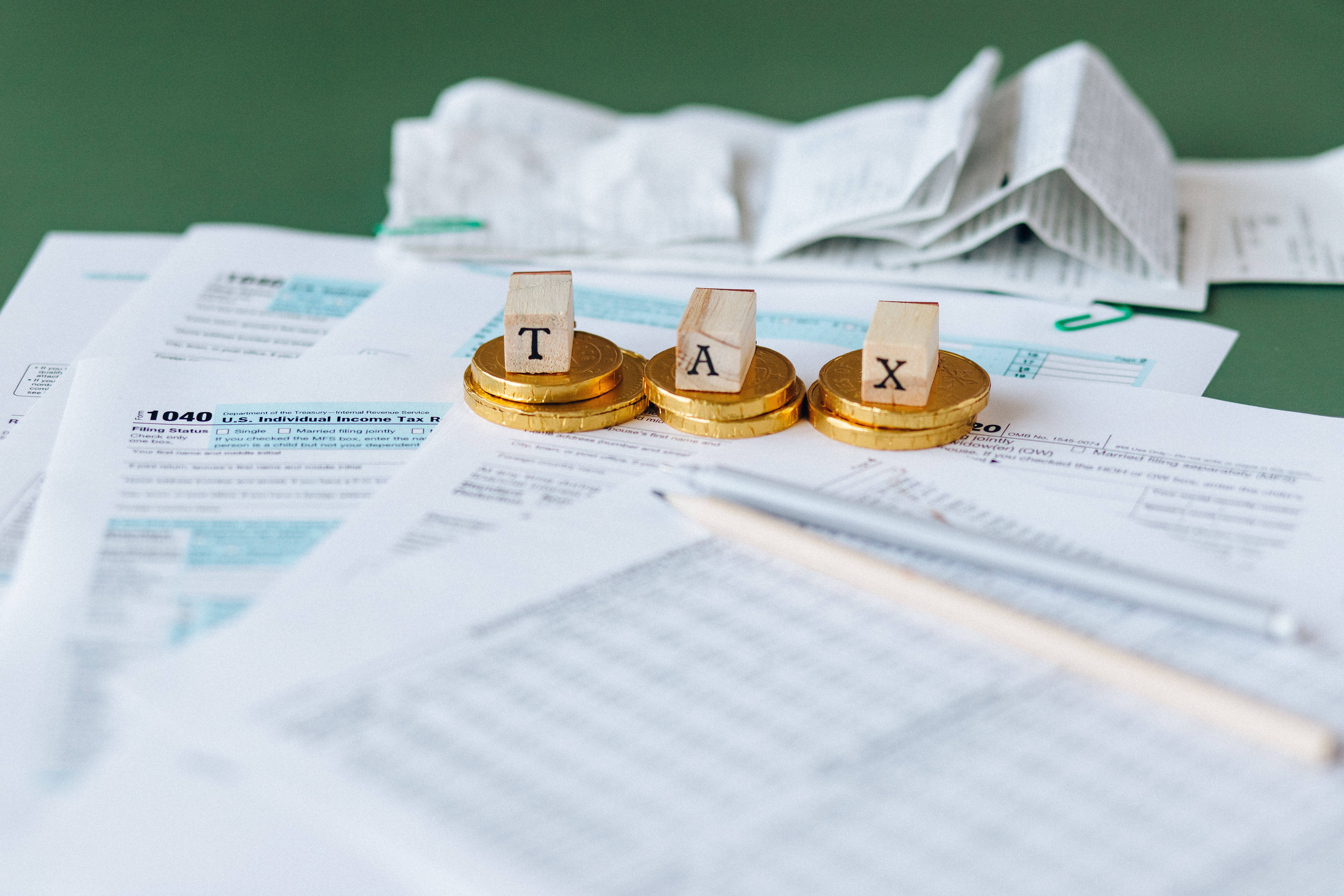 A close-up of a British tax form, a calculator, and scattered coins on a wooden desk