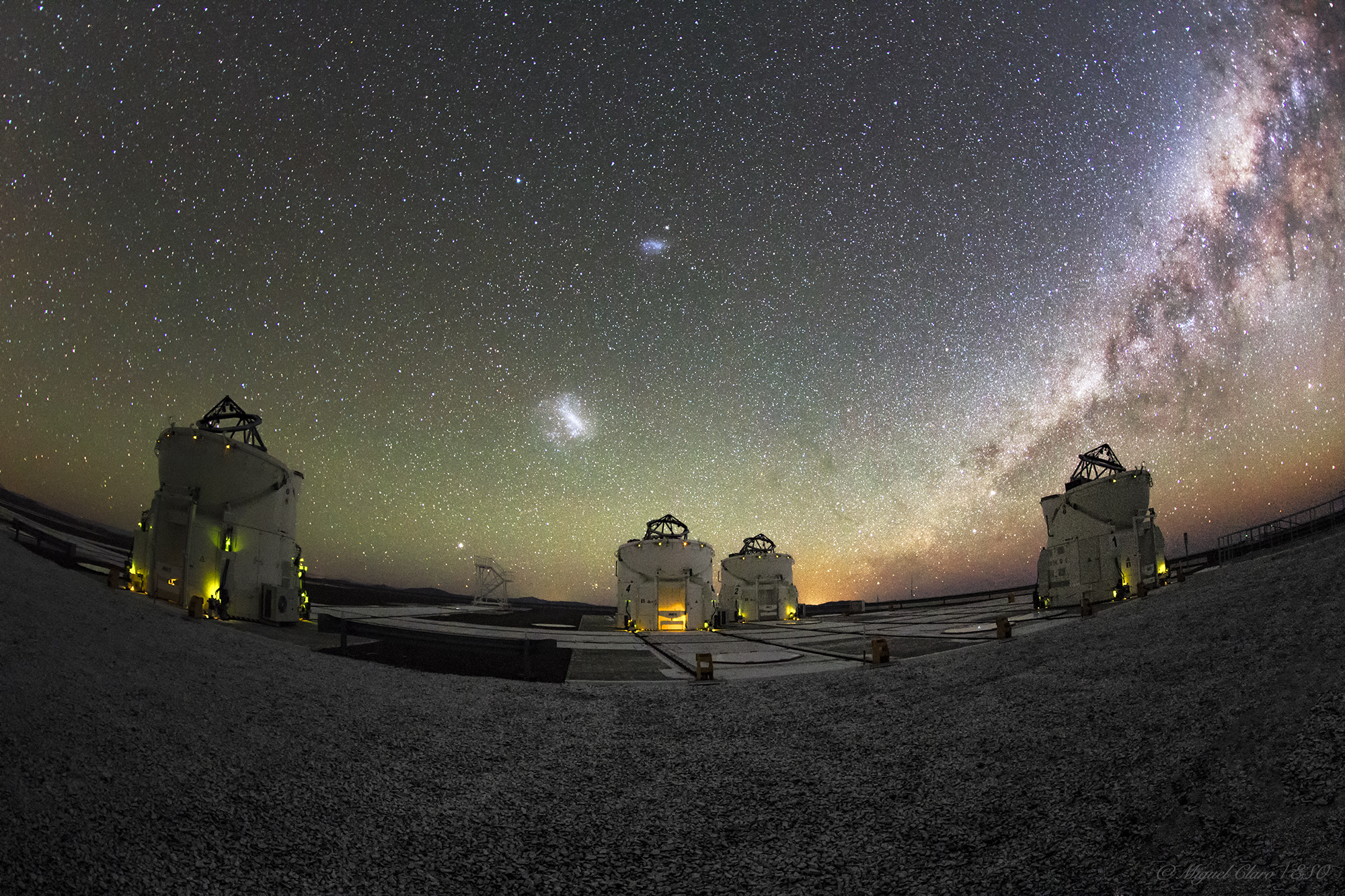Un grand télescope professionnel pointé vers un ciel étoilé la nuit avec des détails de lentille visibles et des environs sombres