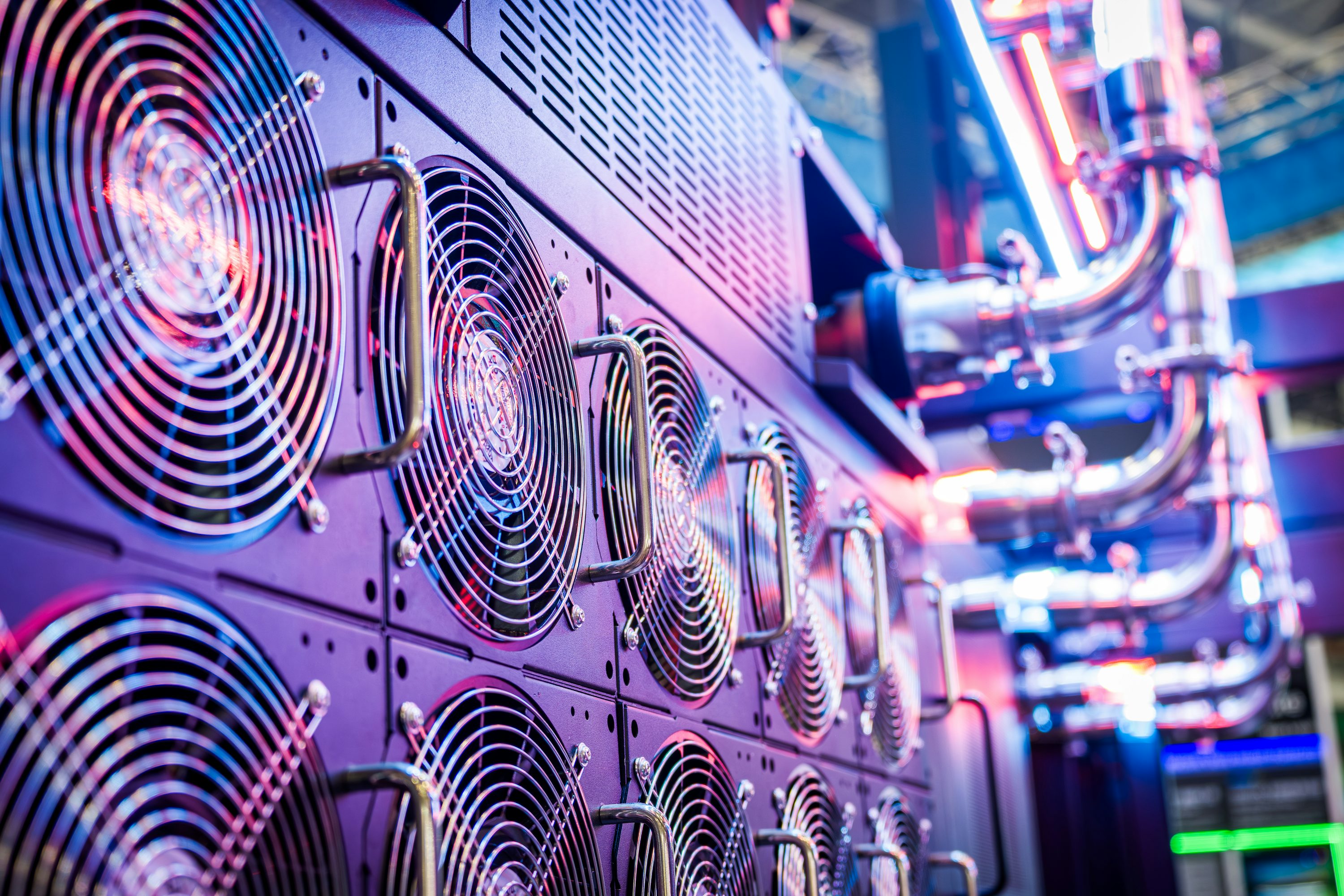 Des rangées de baies de serveurs avec des ventilateurs de refroidissement en rotation et des câbles Ethernet bleus dans un centre de données moderne au Royaume-Uni