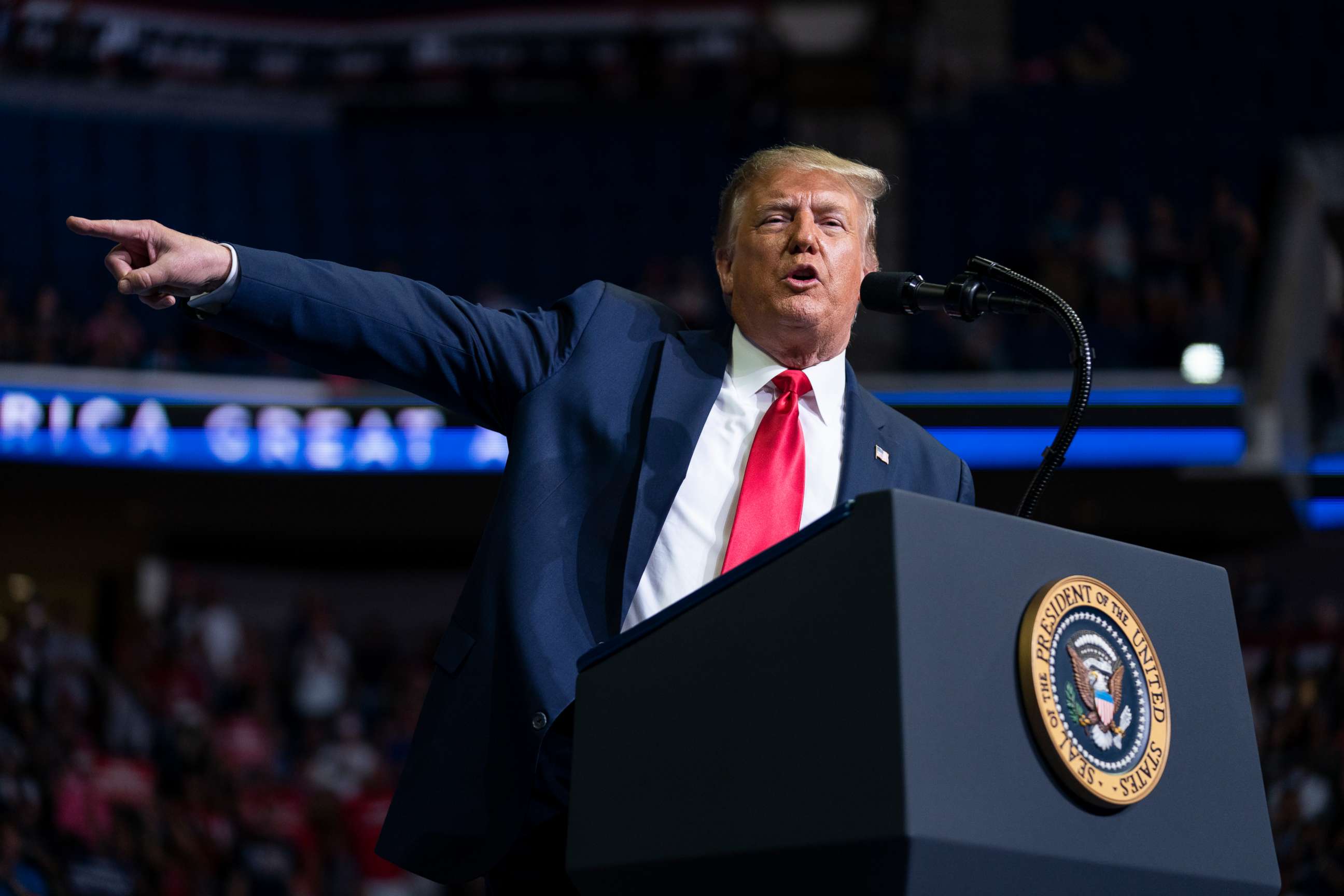 Former President Donald Trump speaking at a rally with American flags in the background