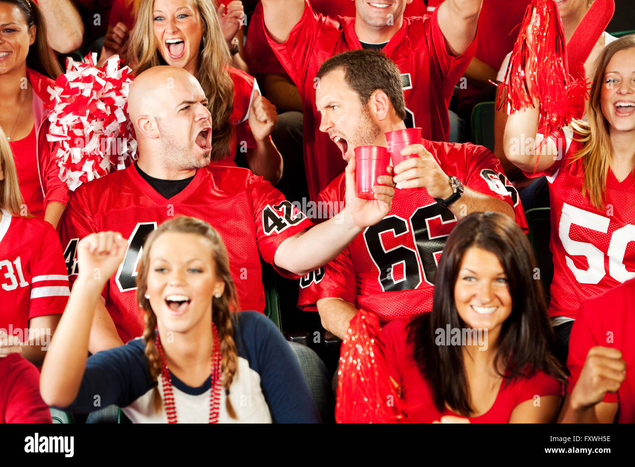 A packed NFL stadium with fans cheering as players run onto the field under bright lights