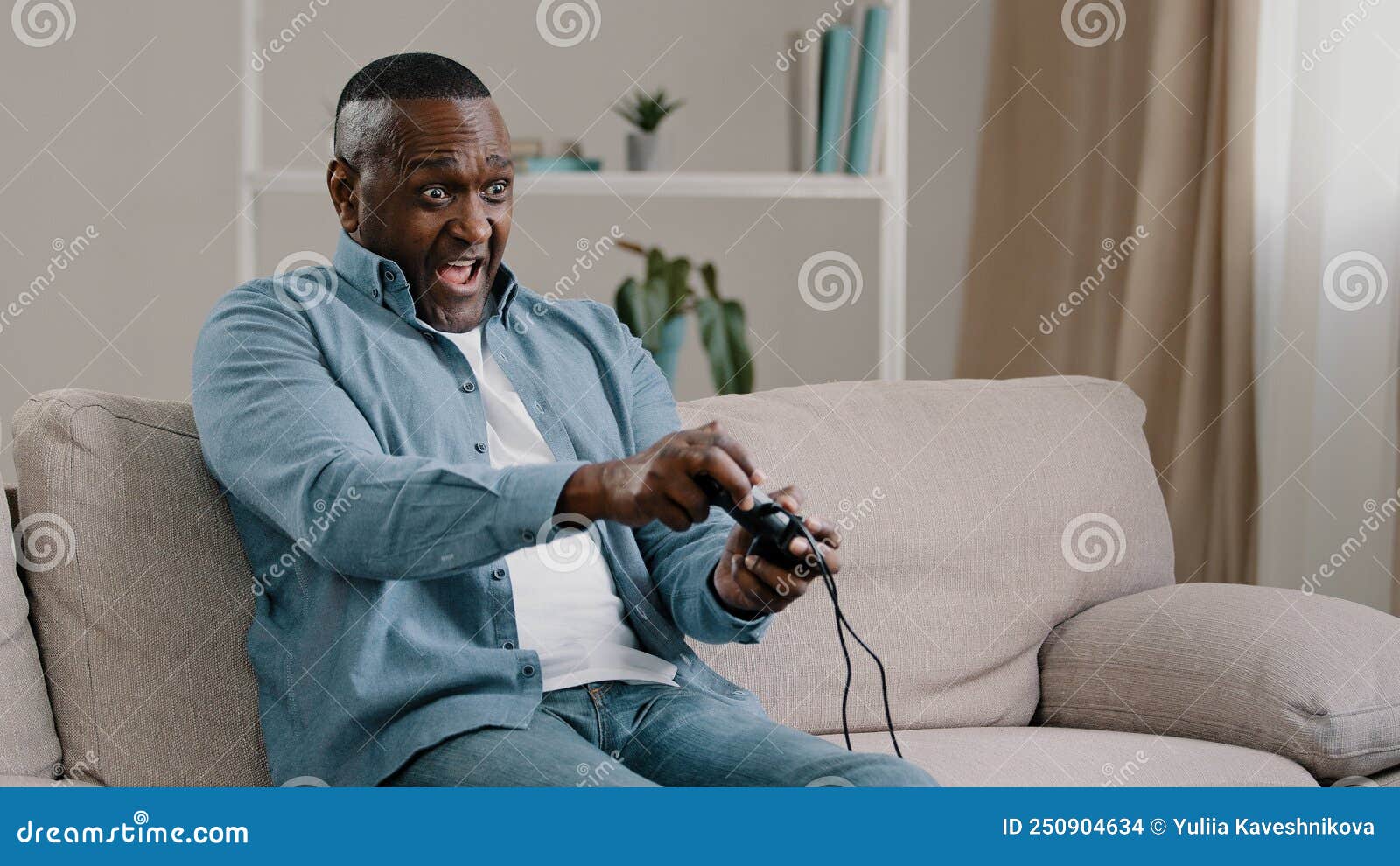 A young gamer holding a wireless controller while sitting on a couch, focused on a large TV screen displaying a high-resolution game scene.