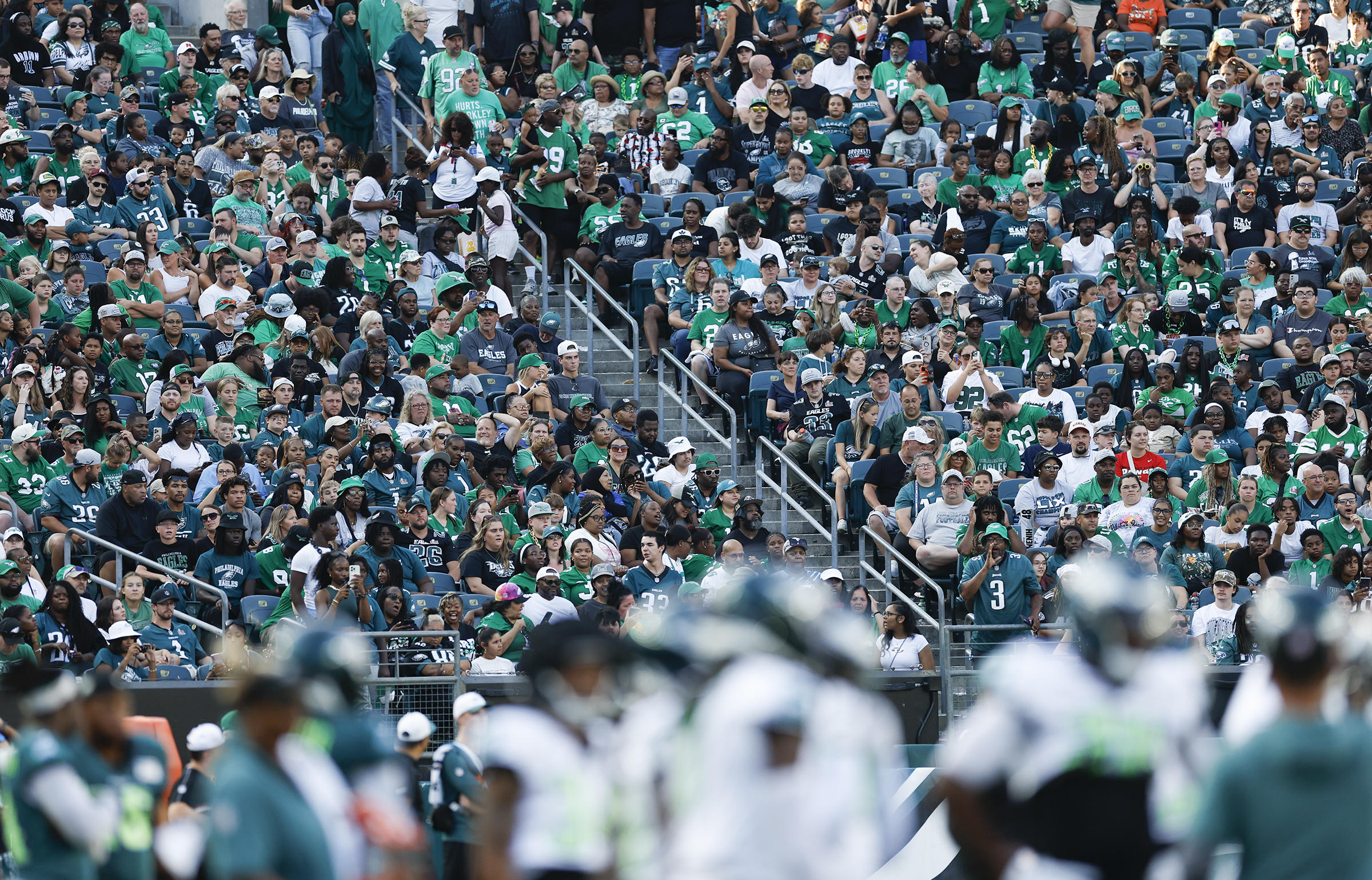 Un stade de football bondé avec des fans portant des vêtements verts et blancs des Eagles de Philadelphie qui crient pendant un match