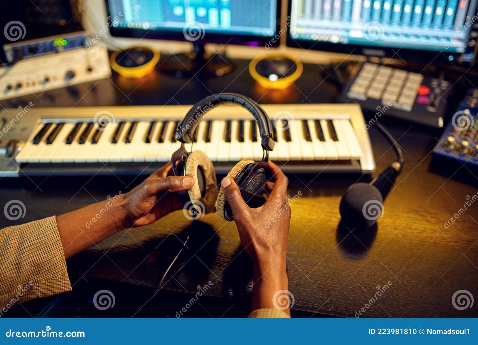Un ingénieur du son professionnel portant des casques supra-auriculaires tout en ajustant les commandes d'une table de mixage dans un studio d'enregistrement sombre.