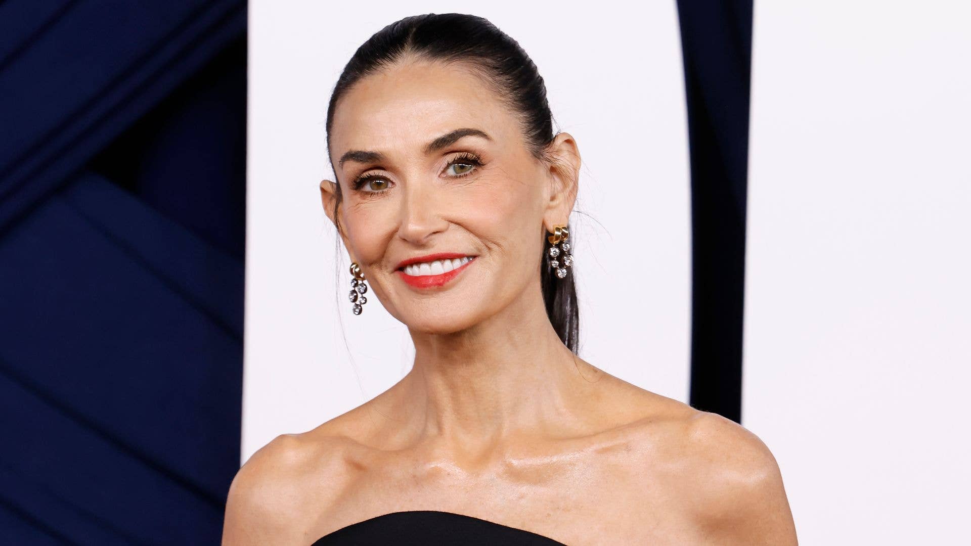 Demi Moore posing on a red carpet in an elegant gown with soft lighting highlighting her features