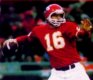 Une photo dramatique en soirée d'un joueur des Broncos de Denver en action contre les Chiefs de Kansas City avec une foule remplie en arrière-plan sous de vives projecteurs