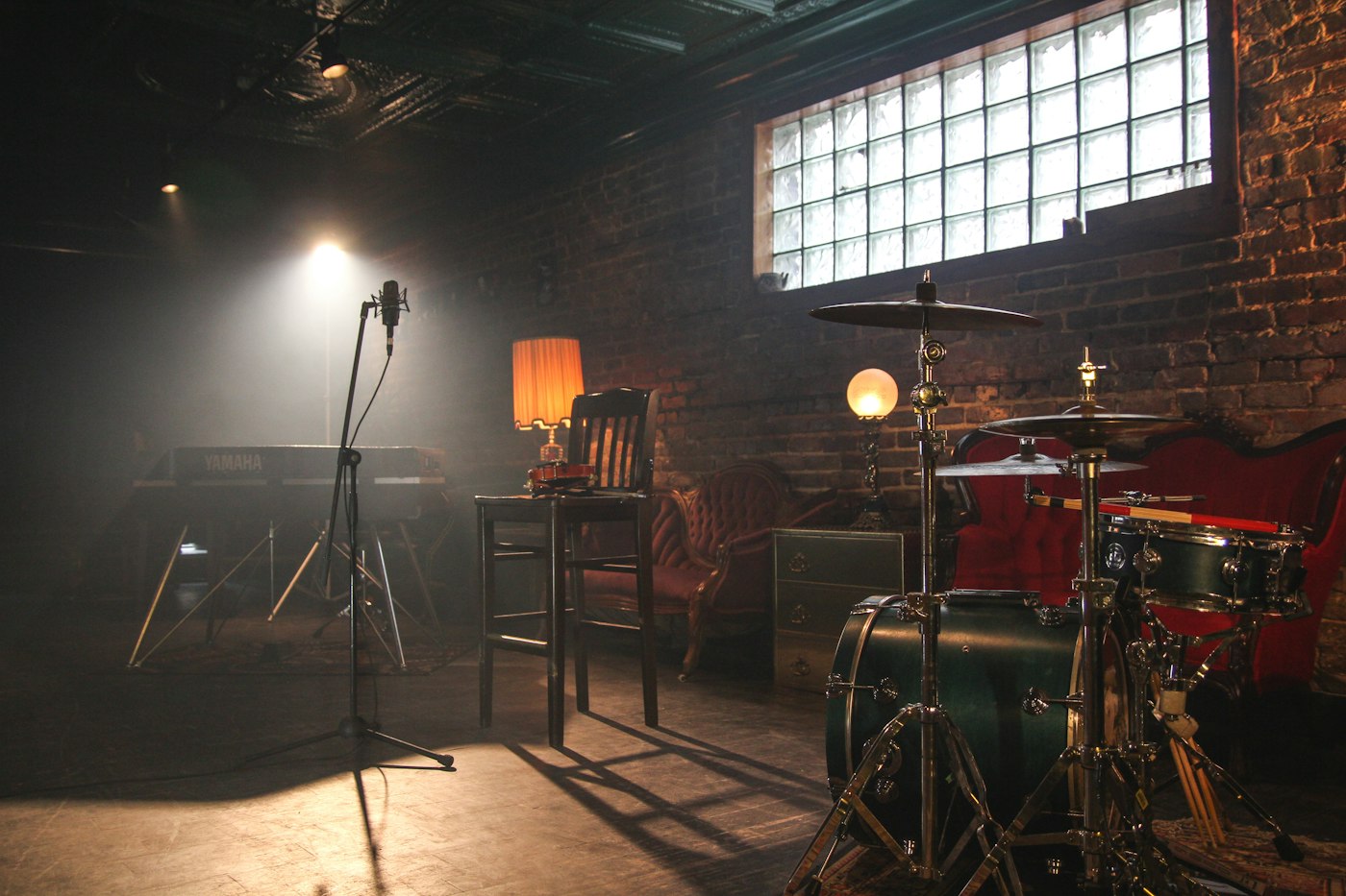 A vintage microphone on a dimly lit stage with a blurred crowd in the background, evoking the atmosphere of a classic French chanson performance.